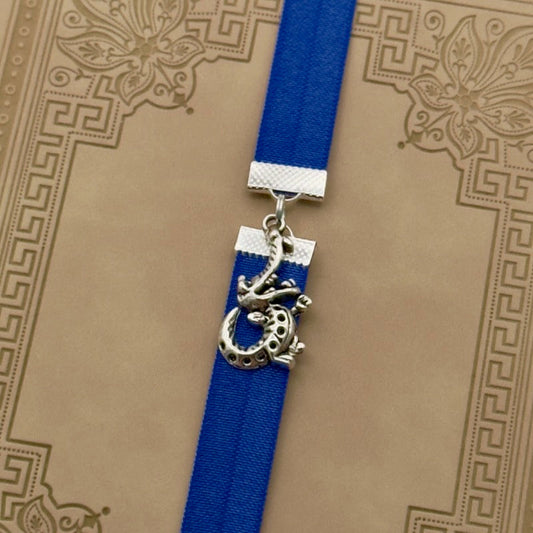 A silver cheerful crocodile charm on an elastic Bookband