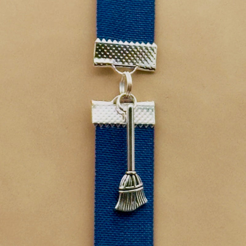 A silver broom charm on an elastic Bookband