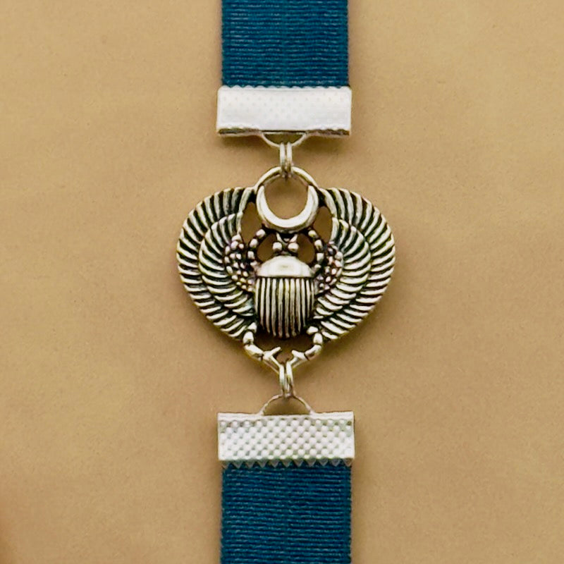 A silver scarab beetle charm on a elastic Bookband