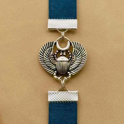 A silver scarab beetle charm on a elastic Bookband
