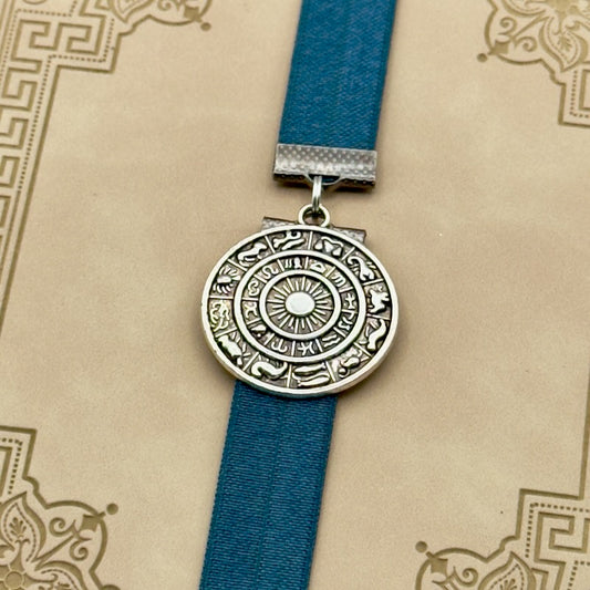 A silver zodiac charm on an elastic Bookband