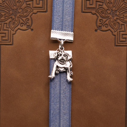 Bookband elastic bookmark with a silver dog design on a metallic blue ribbon on a brown book